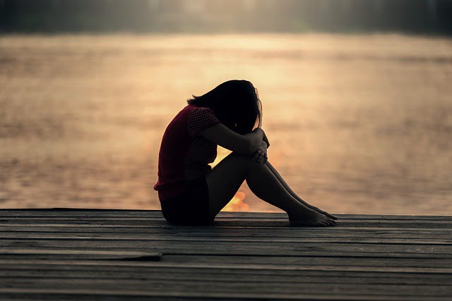 Mulher triste na margem de um lago